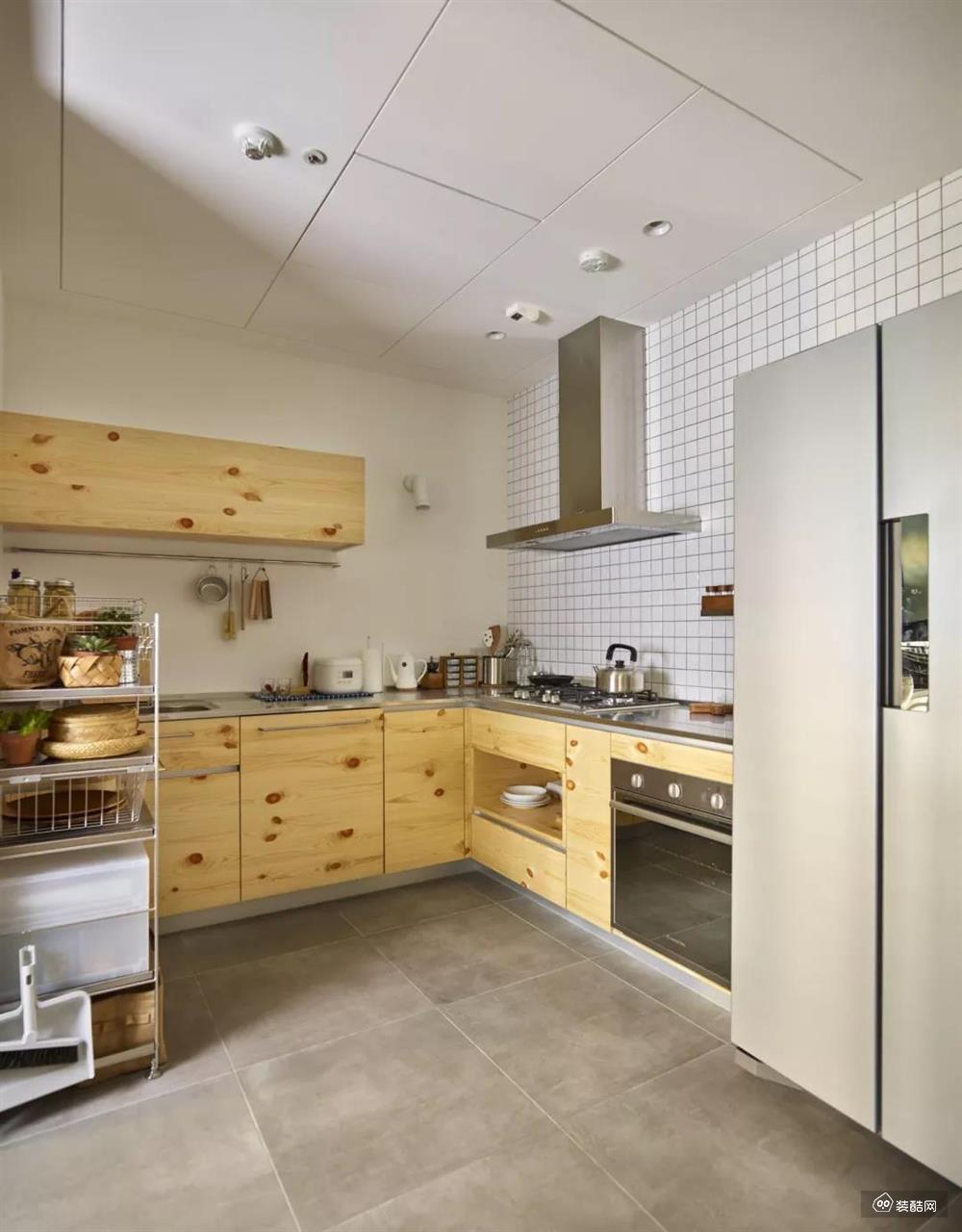 厨房内部做了L型的橱柜，还和生活阳台相连。水泥质感的地砖搭配原木风的橱柜，在简洁轻松当中有着质朴乡村的感觉。