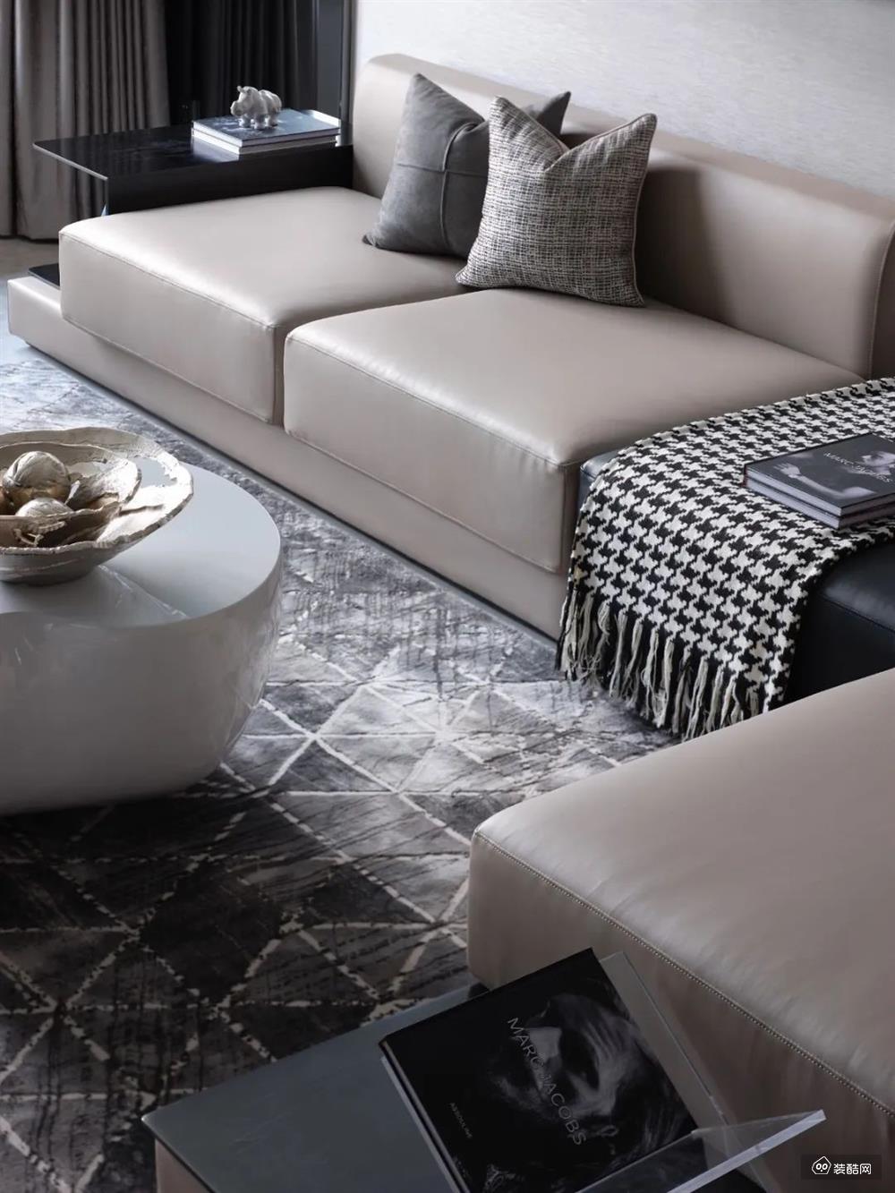 灰色三角图案纹理的地毯,布置卡其色的皮沙发,还有白色的时尚造型茶几