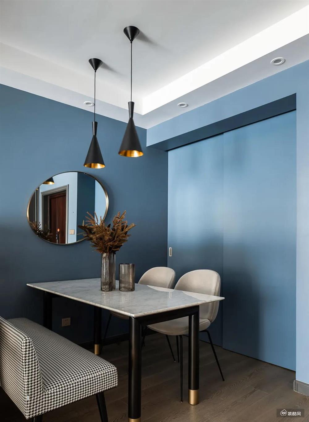 餐厅墙面在蓝色的基础，摆上一张黑色脚+白色石材台面的餐桌，黑白配的设计基础，布置格纹长凳、浅灰色皮艺餐椅，也让用餐氛围显得现代简洁而清爽大方。