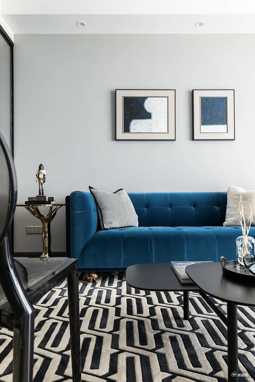 蓝色布艺沙发摆在黑白配的地毯上，边上摆一张金属质感的边几与摆饰品，也让空间显得更加高级档次。