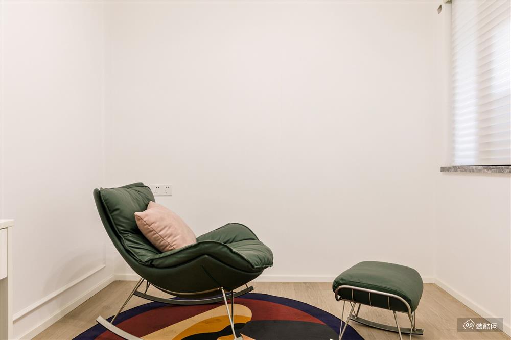 休闲区用墨绿色躺椅和圆形毛毯，打造出一个舒适惬意的小空间，一侧的窗户搭配了百叶帘，简洁中透着轻盈感。