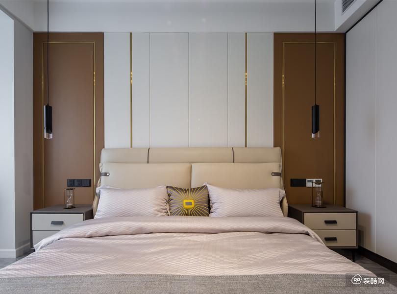 木色，白色和金色条线搭配的墙面让主卧更加惬意。而床和两侧床头柜的布置也最大限度地契合了户型，显得自然且协调。床边的两个黑色吊灯让房间更有情调。