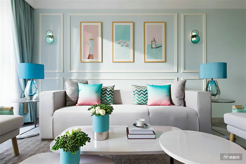 浅灰色的布艺沙发上是蓝粉渐变的抱枕，优雅清新，两侧的蓝调台灯增添了空间的优雅与尊贵。