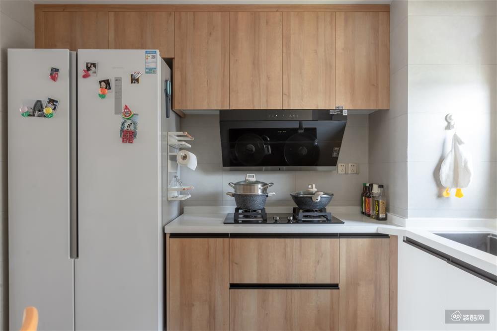 烹饪区破格选用木纹橱柜，让厨房摆脱了油腻的刻板印象。爵士白的瓷砖做底色，整体看起来干净又高级。除此之外，特意挤出一个冰箱位，内凹入墙，形成科学合理的动线。